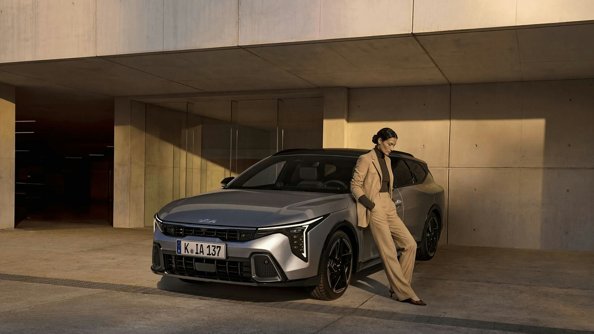 Eine Frau lehnt an den KIA K4 Sportswagon