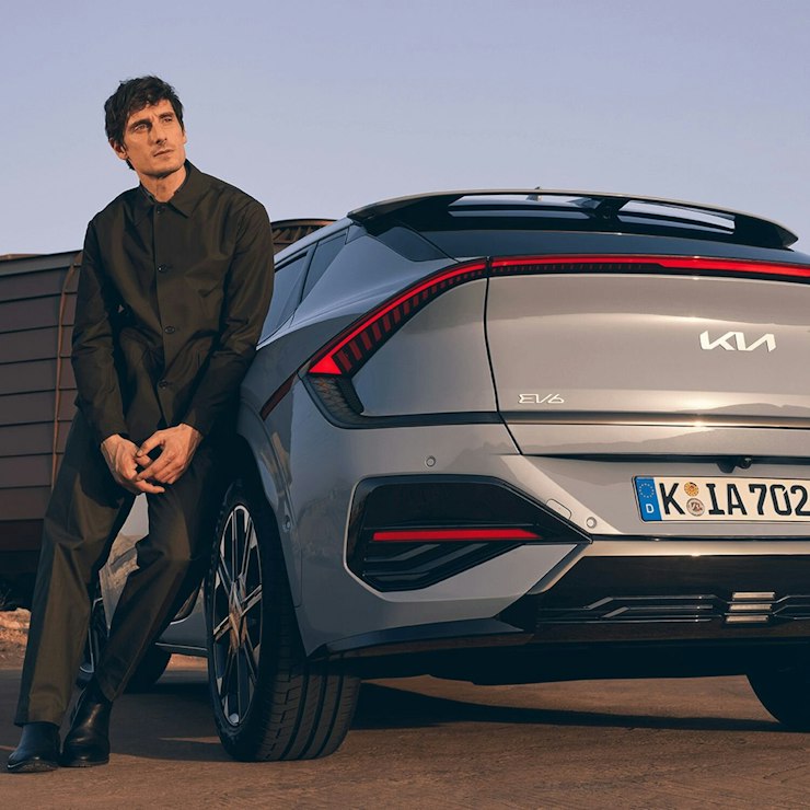 Ein Mann lehnt sich an das Heck des Kia EV6