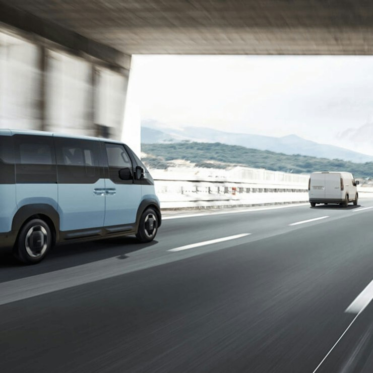 Kia PV5 WAV auf der Autobahn mit aktivem Autobahnassistenten, der dabei unterstützt, Geschwindigkeit, Sicherheitsabstand und Spurposition beizubehalten.