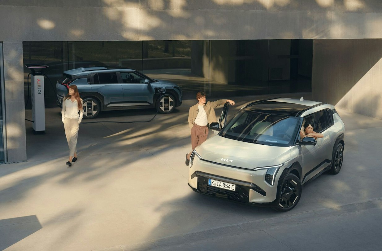 Mehrere Personen stehen um zwei Kia EV3 herum, welche am Laden sind.