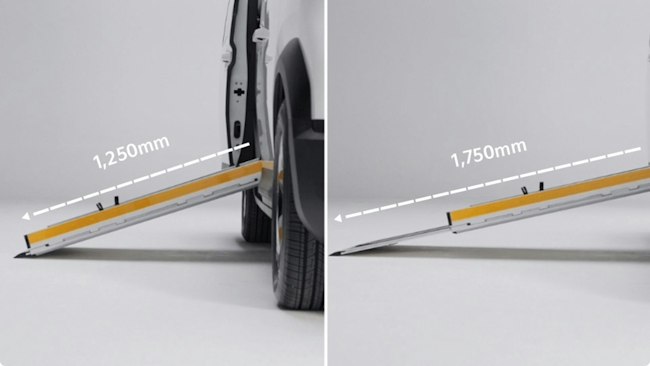 Eine Person fährt die zweiteilige, im Fahrzeugboden integrierte Rampe am Seiteneinstieg des Kia PV5 WAV aus, um den Einstieg mit einem Rollstuhl zu ermöglichen.