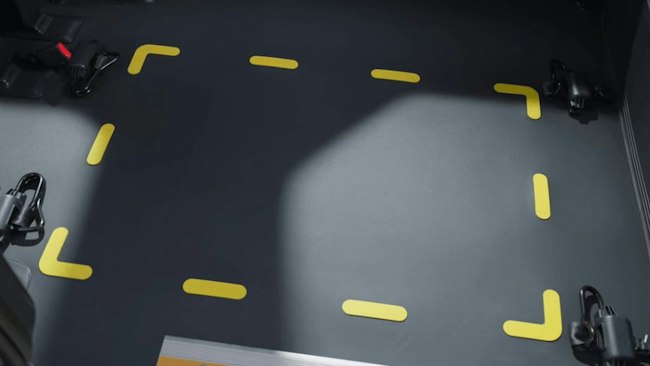 Ein Rollstuhl ist im Kia&nbsp;PV5&nbsp;WAV positioniert, während eine Person den Rollstuhlrahmen mit dem im Fahrzeugboden verankerten Rückhaltesystem sichert.