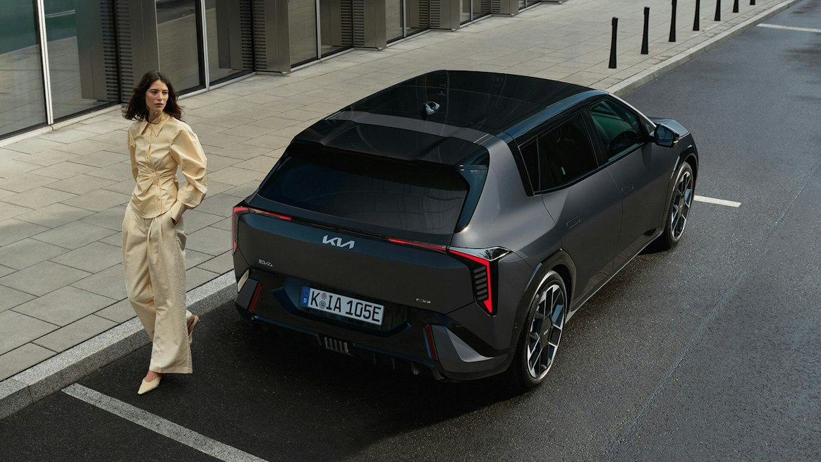Eine Frau lehnt sich an die Fronttür des Kia EV4 GT