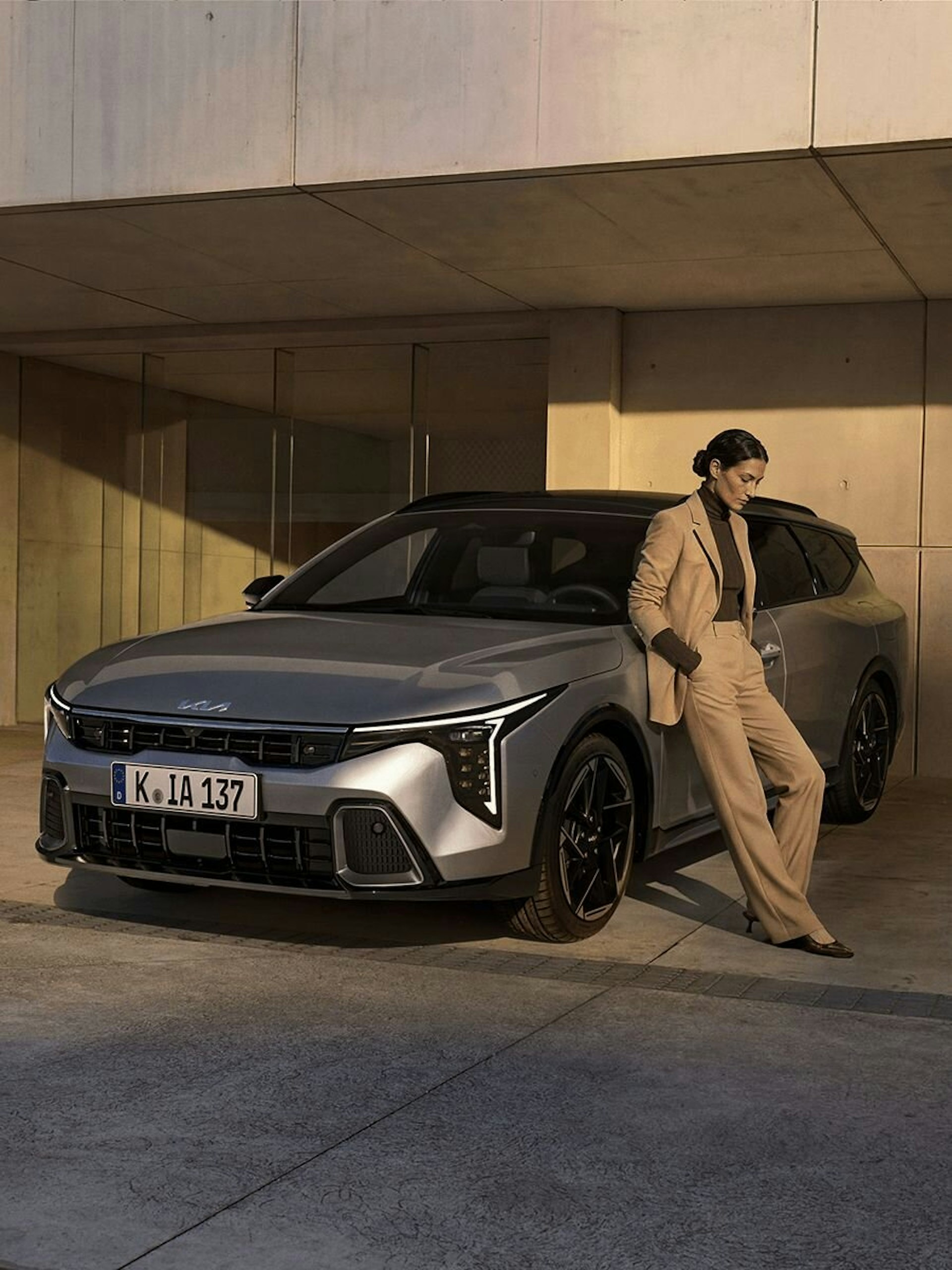 Eine Frau lehnt an den KIA K4 Sportswagon