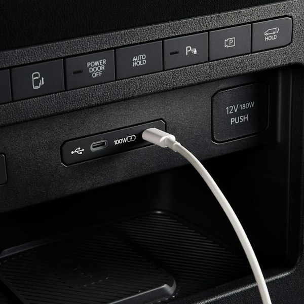 Nahaufnahme eines 100-W-USB-C-Anschlusses im vorderen Innenraum des Kia&nbsp;PV5&nbsp;WAV beim Laden eines Geräts.