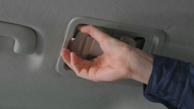 Eine Person hilft dabei, den 3-Punkt-Sicherheitsgurt einer im Rollstuhl sitzenden Person im Kia PV5 WAV anzulegen.