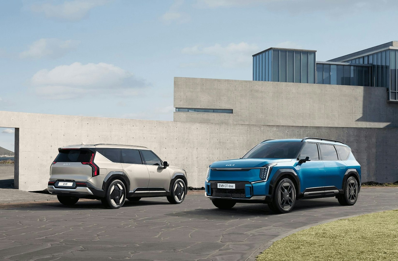 Zwei Kia EV9 stehen bei einem Gebäude